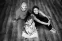 Ambiance noir et blanc, deux parents et deux enfants, dont un tout petit bébé, sont assis au sol et posent pour une photo de famille