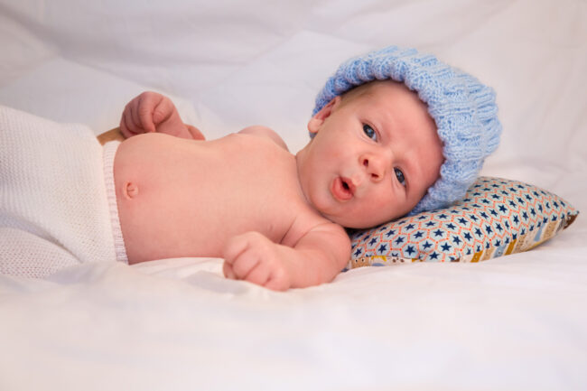 Pablo, un bébé de trois mois allongé sur un lit, fait une grimace