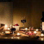 apéritif servi de nuit en terrasse sur une table en palette avec bougies, vin, charcuterie.