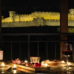 Apéritif de nuit sur une terrasse privée, face à la Cité de carcassonne, ambiance bougie.