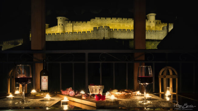 Apéritif de nuit sur une terrasse privée, face à la Cité de carcassonne, ambiance bougie.