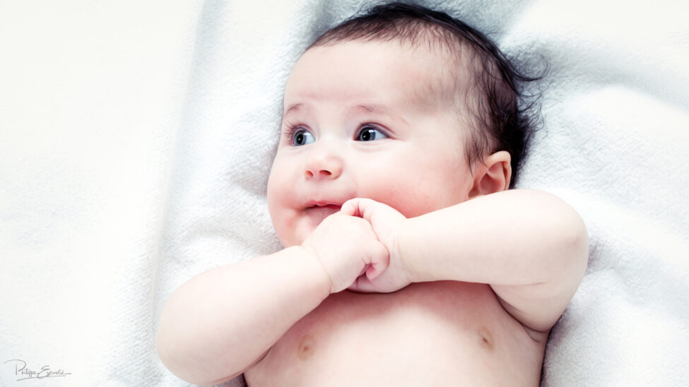 Bébé photographié en studio se tenant les mains entrelacées