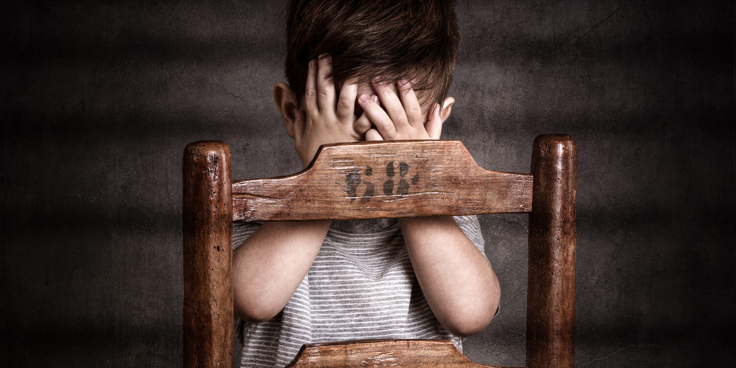 Enfant photographié en studio avec les mains se masquant le visage
