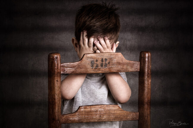 Enfant photographié en studio avec les mains se masquant le visage