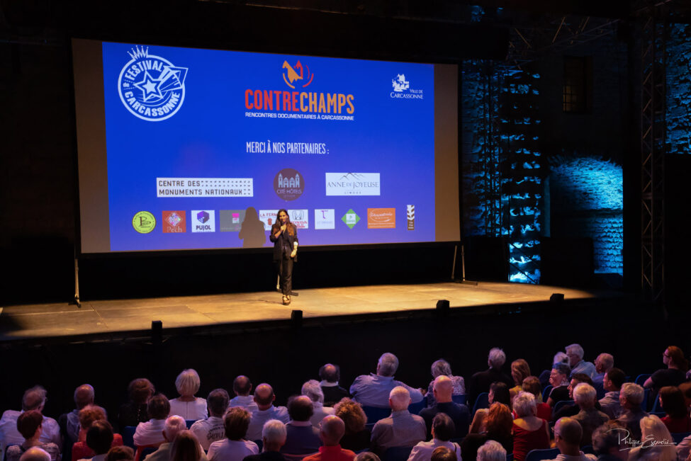 Micro à la main, un grand écran derrière elle, Laurence Gasc s'addresse au public assis