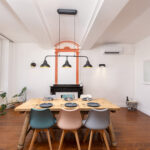 Élégante salle à manger avec un parquet en bois, une grand table en bois dressée et une rampe de luminaires au dessus de la table.