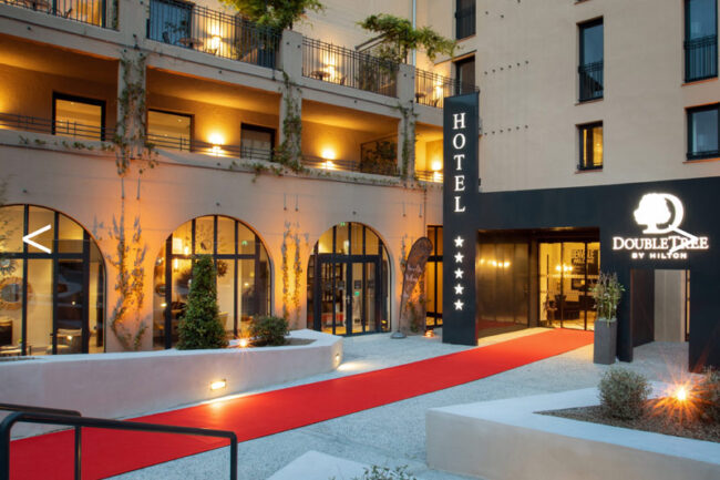 Entrée d'un hôtel hilton cinq étoiles avec un tapis rouge accueillant en fin de journée