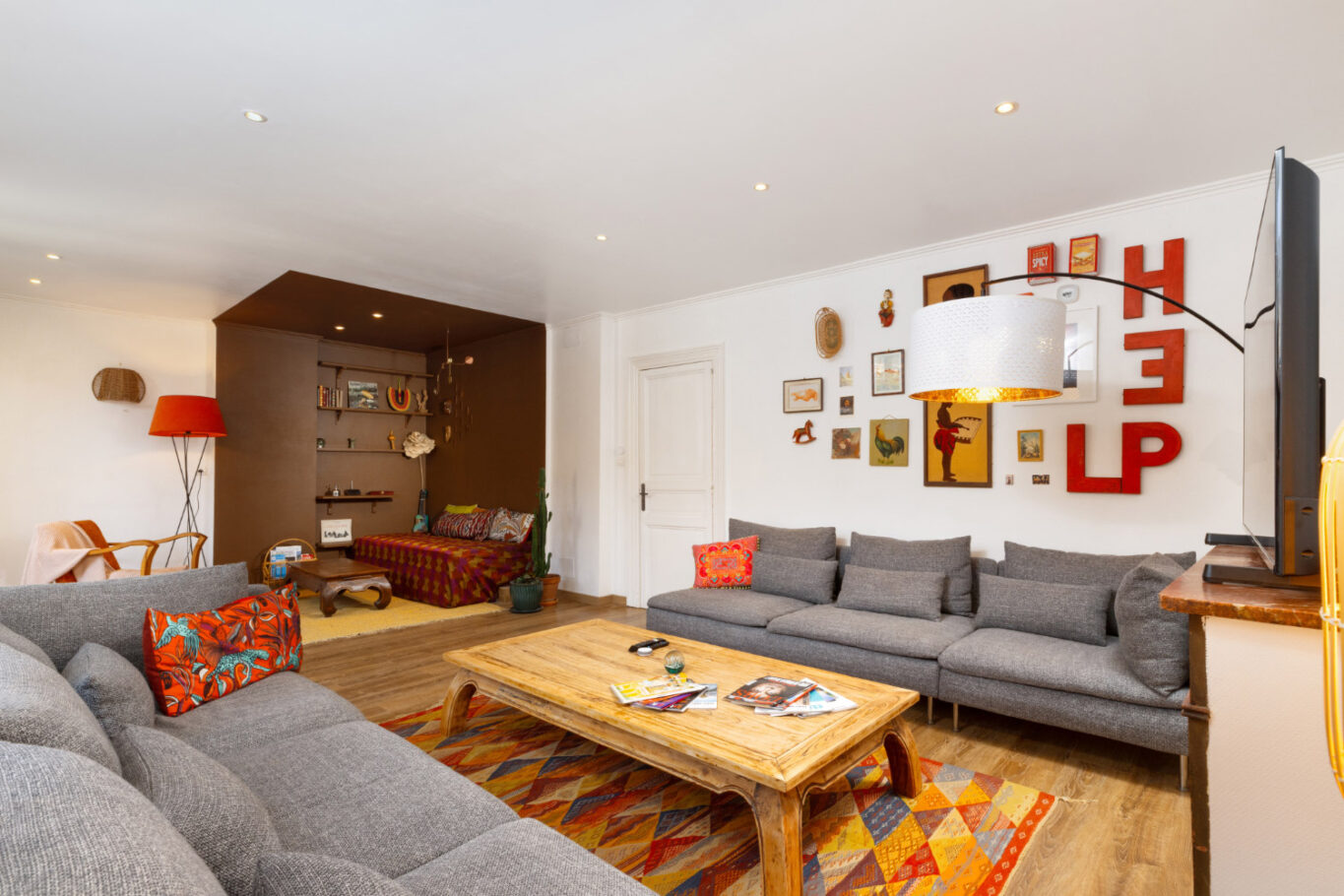 un grand salon avec une table en bois et deux canapés gris donnant une atmosphère cosy