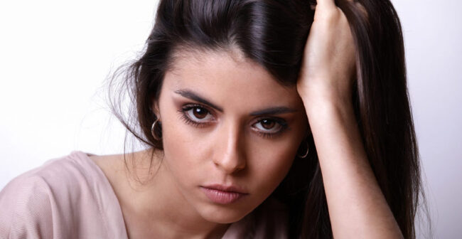 Gros plan visage d'une jeune mannequin la main dans les cheveux