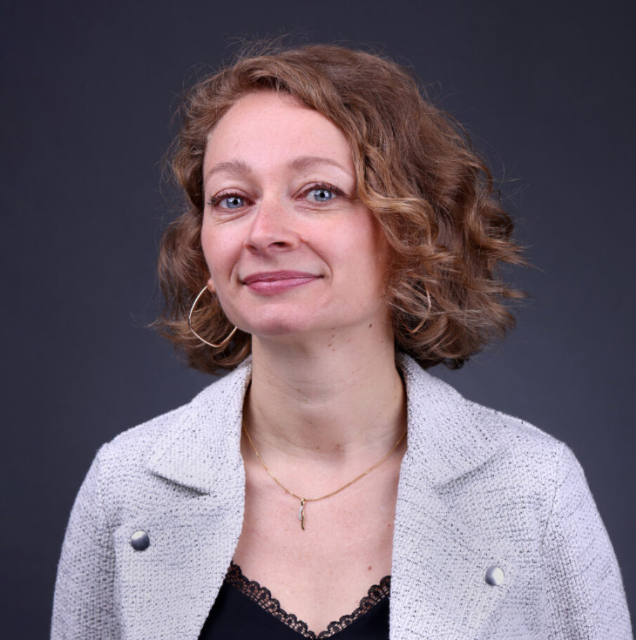 Portrait de face d'une femme souriante avec des yeux clairs et une boucle d'oreille