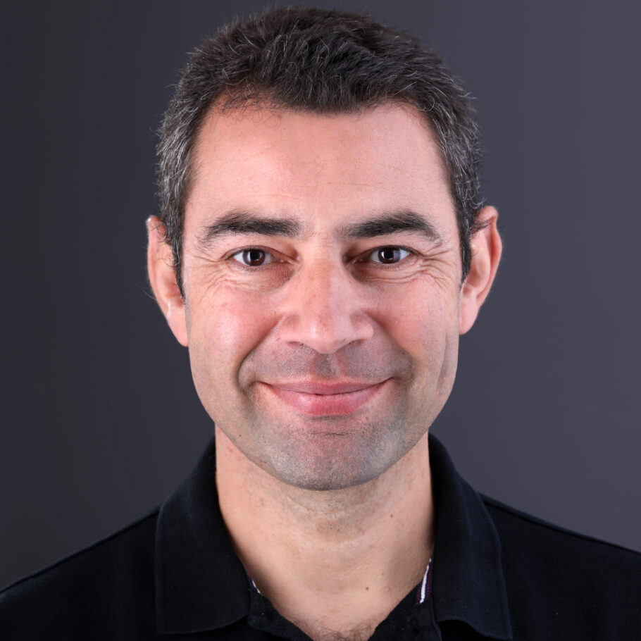 Un homme en chemise noire sourit joyeusement à l'objectif