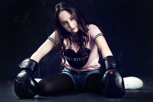 Une adolescente assise avec des gants de boxes enfilés