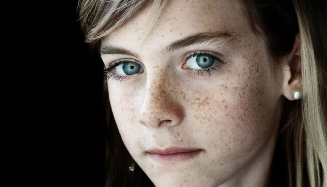 Visage d'une enfant aux yeux bleus et avec des taches de rousseur