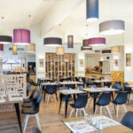 salle de restaurant avec des tables dressées, des chaise et de nombreux luminaires au plafond