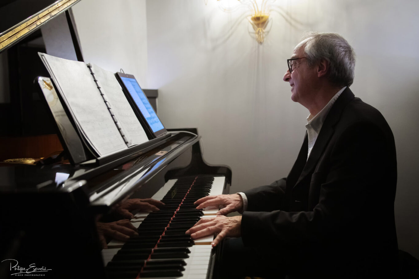un pianiste souriant joue du piano en regardant sa partition