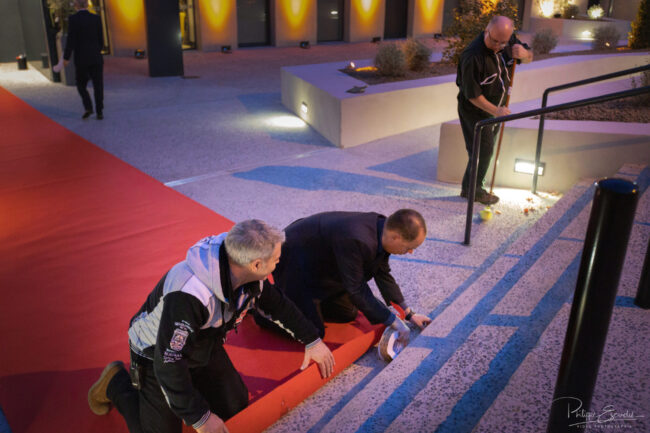 Inauguration de l'hôtel Hilton de Carcassonne 16 Deux personnes accroupies scotchent le tapis rouge de l'hôtel
