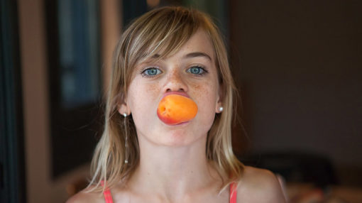 une petite fille un abricot dans la bouche