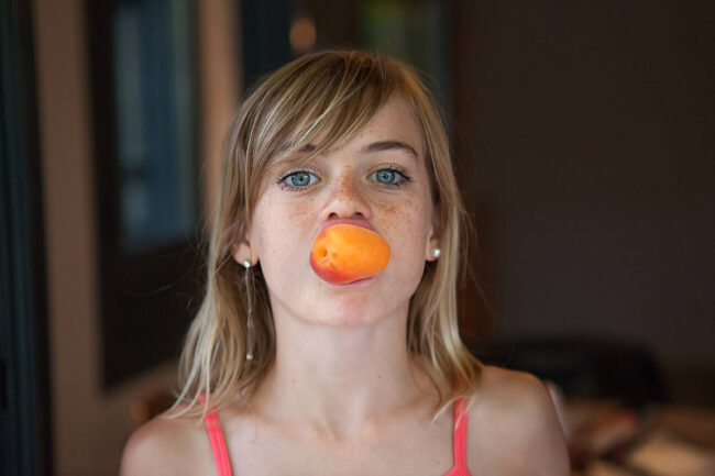 une petite fille un abricot dans la bouche