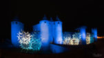Projection de nuit de formes en demi-lune sur les murailles du château comtal éclairées en bleu