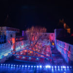 vue en plongée du château comtal de nuit avec dans la cour du midi un chapiteau transparent et des tables dressées à l'intérieur.