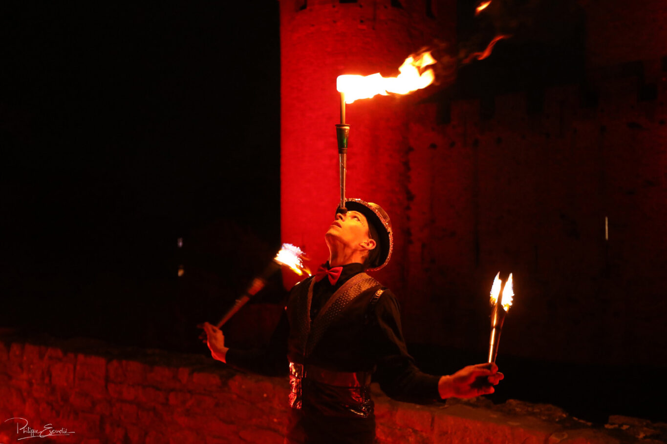 Jongleur de feu de nuit avec une torche sur le nez et la cité de Carcassonne en arrière-plan
