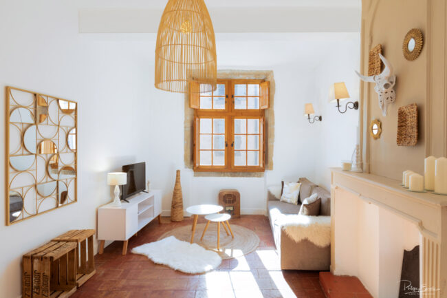 Photos immobilières du mois 1 salon ajouré avec deux grand murs blancs un canapé un téléviseur et du mobilier en bois