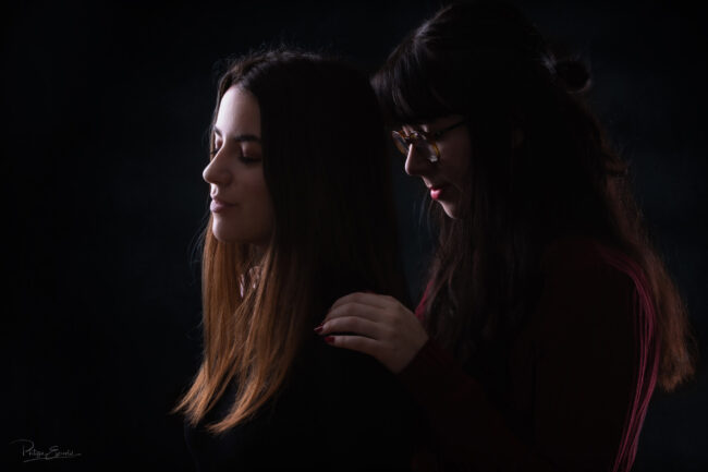 Deux filles, l'une derrière l'autre, les yeux fermés dans la pénombre