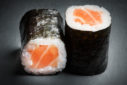gros plan de deux hoso makis au saumon présentés sur une ardoise