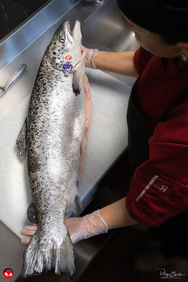 saumon avec une étiquette label rouge dessus tenu par une cuisinière