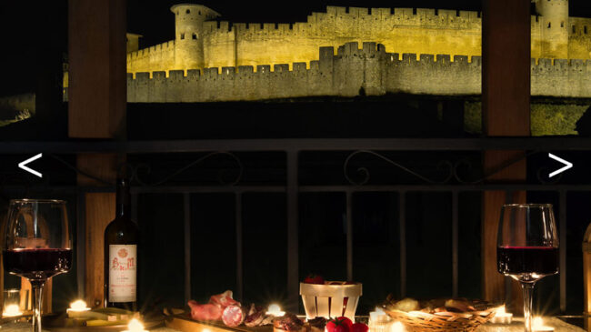 table avec bougie et apéritif de nuit avec cité médiévale en arrière plan