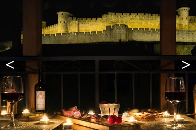 table avec bougie et apéritif de nuit avec cité médiévale en arrière plan