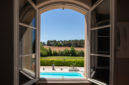 fenêtre ouverte avec vue sur une piscine et des montagnes à l'horizon