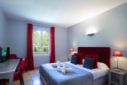 chambre avec grand lit simple parure grise drap blanc, tenture rouge