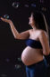 Une femme enceinte lève sa main vers une bulle de savon