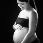 Une femme enceinte de profil en noir et blanc se tient le ventre