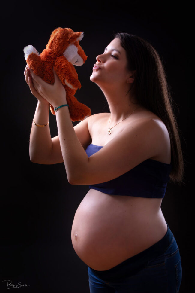 Une femme enceint tient dans les mains une peluche