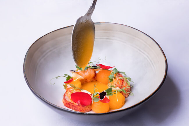 Dans les cuisines du Puits du Trésor, Lastours 3 cuillère laissant échapper une goutte de sauce sur des ingrédients dans un bol