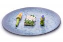 grande assiette bleue avec dedans une fleur de courgette, un poisson avec une crème blanche dessus et une courgette avec des fleurs