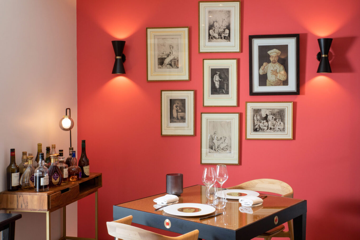 Table dressée de restaurant avec à l'arrière un mur orange sur lequel sont accrochés des dessins