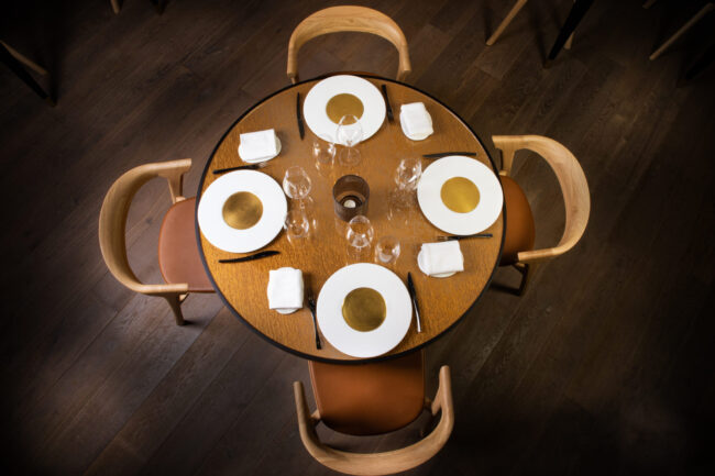 Restaurant Le Puits du Trésor, Lastours 3 Quatre assiettes avec couverts sur une table ronde vue de dessus