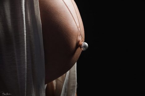 ventre d'une femme enceinte avec un pendantif sur le nombril