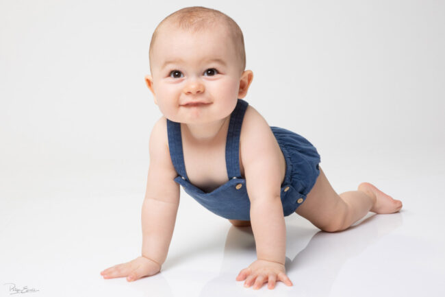 En famille, formule box cadeau ! 6 un bébé allongé au sol se redresse sur ses mains et pince ses lèvres