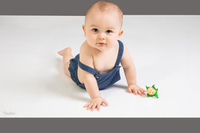 En famille, formule box cadeau ! 7 un bébé en salopette bleu regarde fixement face à lui