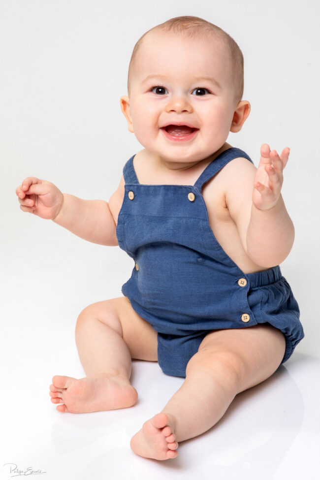 En famille, formule box cadeau ! 10 Un bébé souriant est assis surfond un blanc