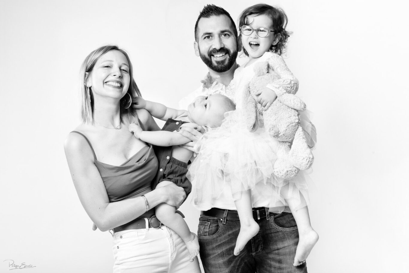 une famille composée d'un homme d'une femme d'une fillette et d'un bébé. Les parents tiennent chacun un enfant dans les bras.