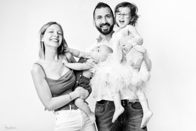 une famille composée d'un homme d'une femme d'une fillette et d'un bébé. Les parents tiennent chacun un enfant dans les bras.