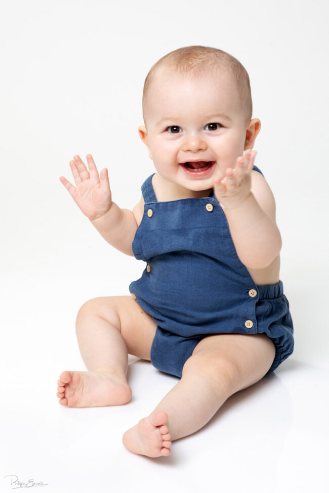 En famille, formule box cadeau ! 17 Un bébé est assis sur un fond blanc et sourit