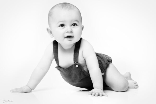 En famille, formule box cadeau ! 18 Un bébé en salopette est allongée sur un fond blanc