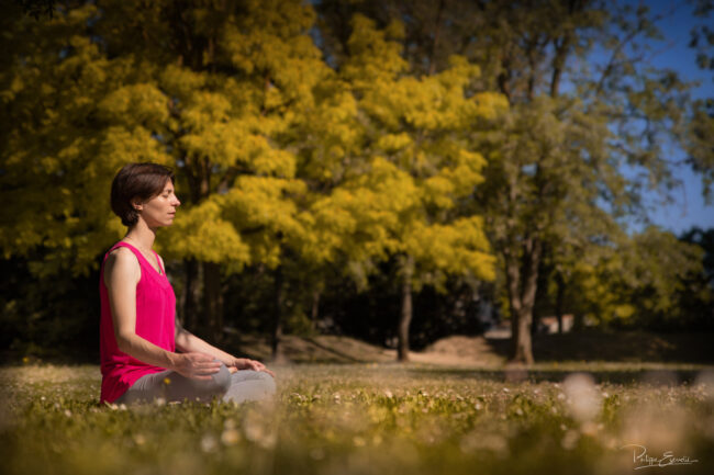 Esprit Tellurique es-tu là ? 2 Une fille médite en position de yoga les mains sur les genoux, assise dans une prairie.