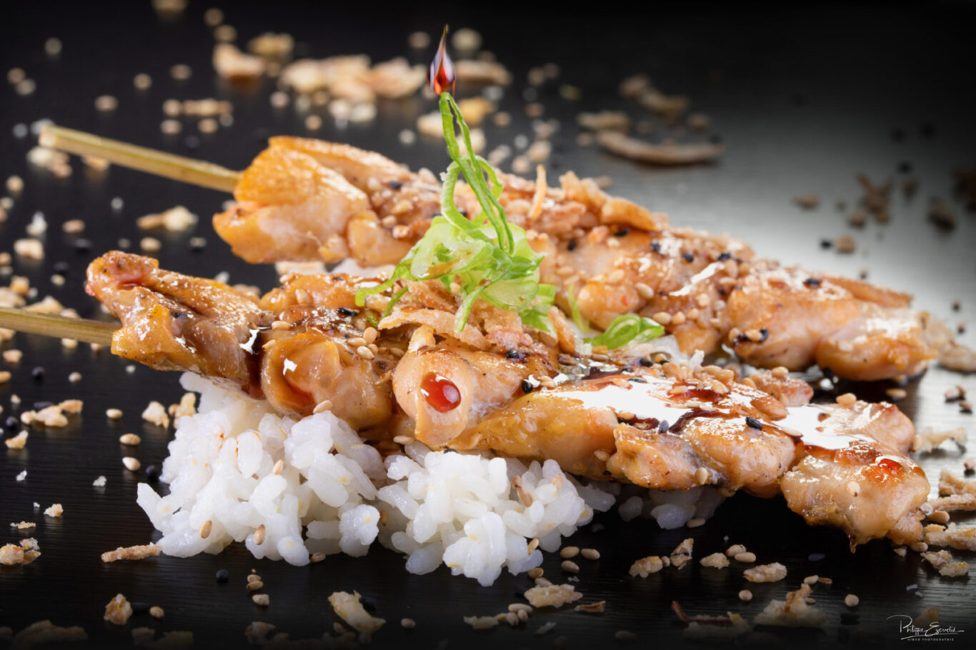 Deux brochettes de yakitori poulet posées sur du riz